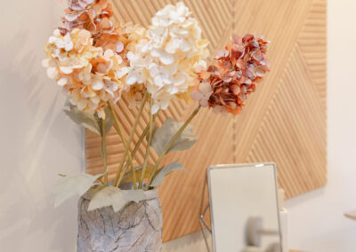 Dried orange flowers in a ceramic vase on a wood console table.