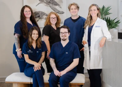 Palm Valley Eye Care team of six smiling staff members in navy scrubs and a white coat, posing together in the office.